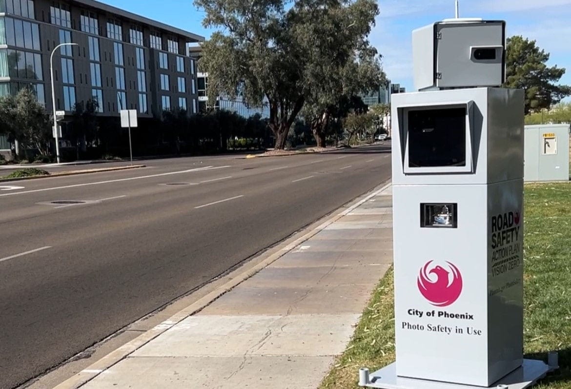 A City of Phoenix Photo Safety System, in the form of a gray metal box resembling a utility box, located along a Phoenix arterial street.